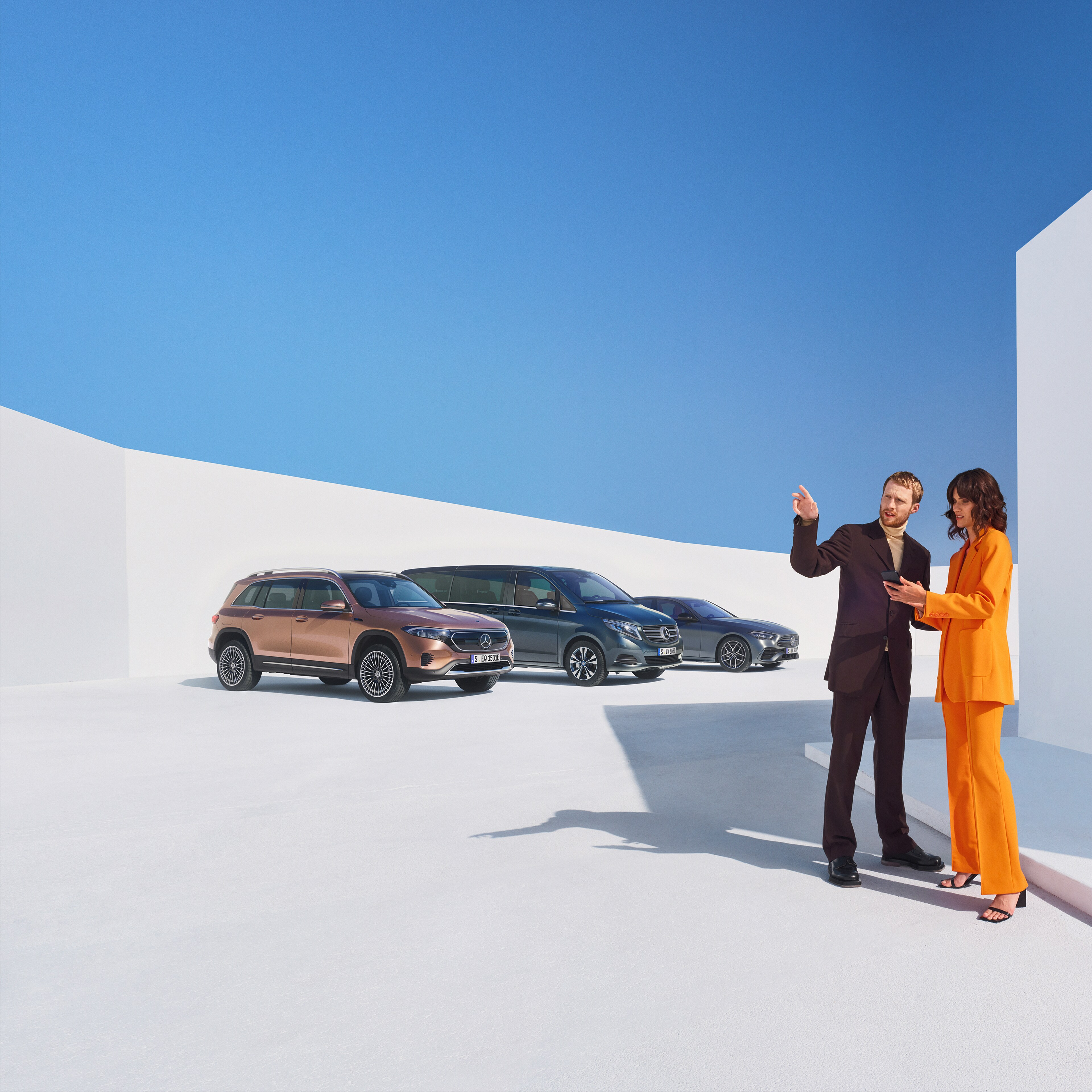 Two people talking about Digital Extras for business customers. Three Mercedes-Benz vehicles can be seen in the background.