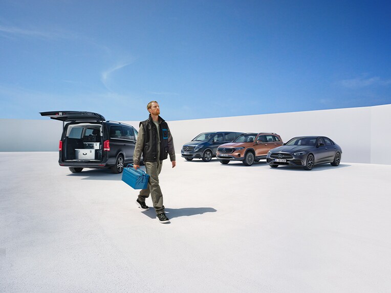 บุคคลถือสมาร์ทโฟนที่เชื่อมต่ออยู่กับรถยนต์ Mercedes-Benz ผ่าน Digital Extras