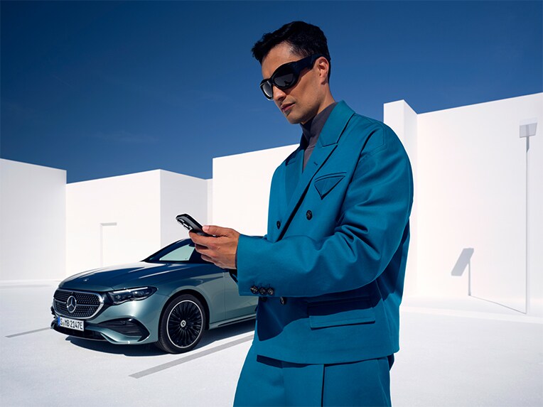 ผู้ชายคนหนึ่งเชื่อมต่อกับรถยนต์ Mercedes-Benz ด้วยสมาร์ทโฟน
