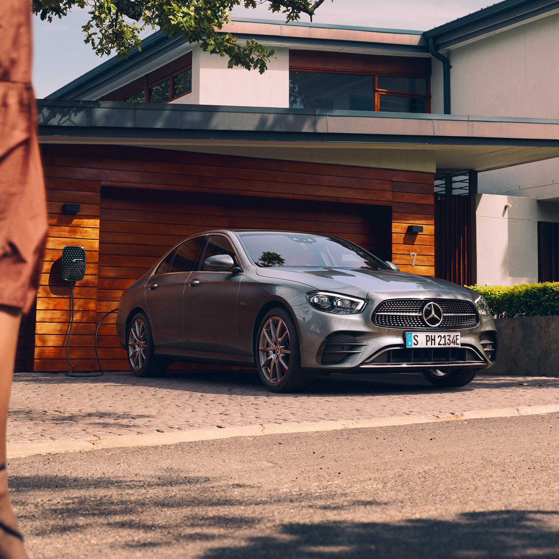Plug-in hybrid: electric motor and internal combustion engine perfectly combined | Electric mobility | Mercedes-Benz The image shows the Mercedes-Benz E-Class Saloon being charged outside a garage.