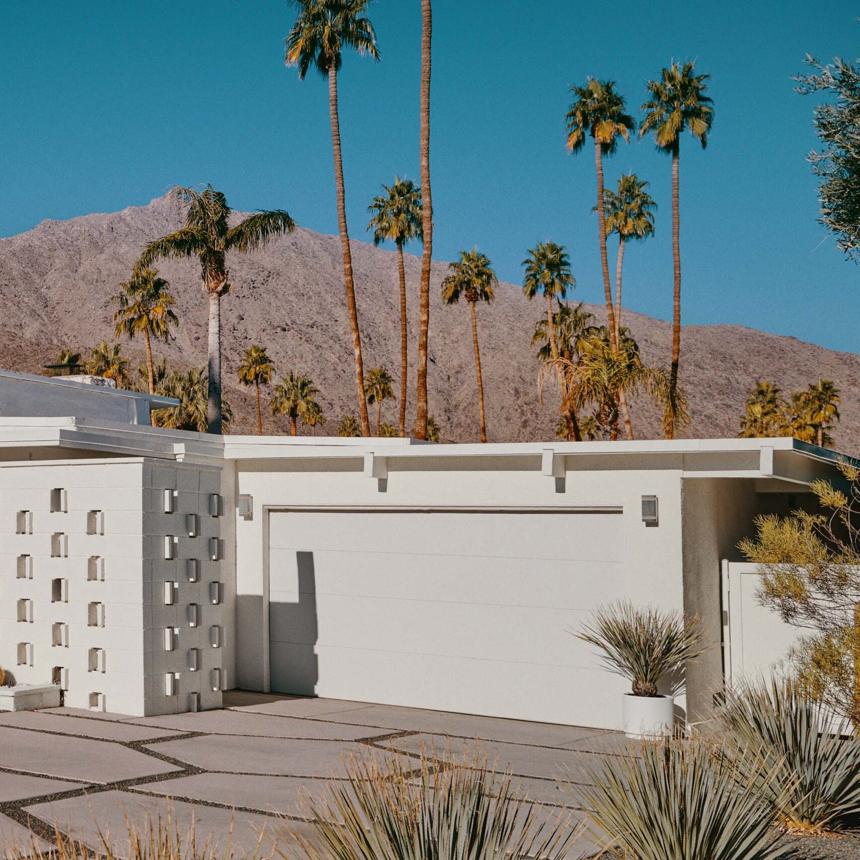 A white suburban architect house with a driveway and a garage.