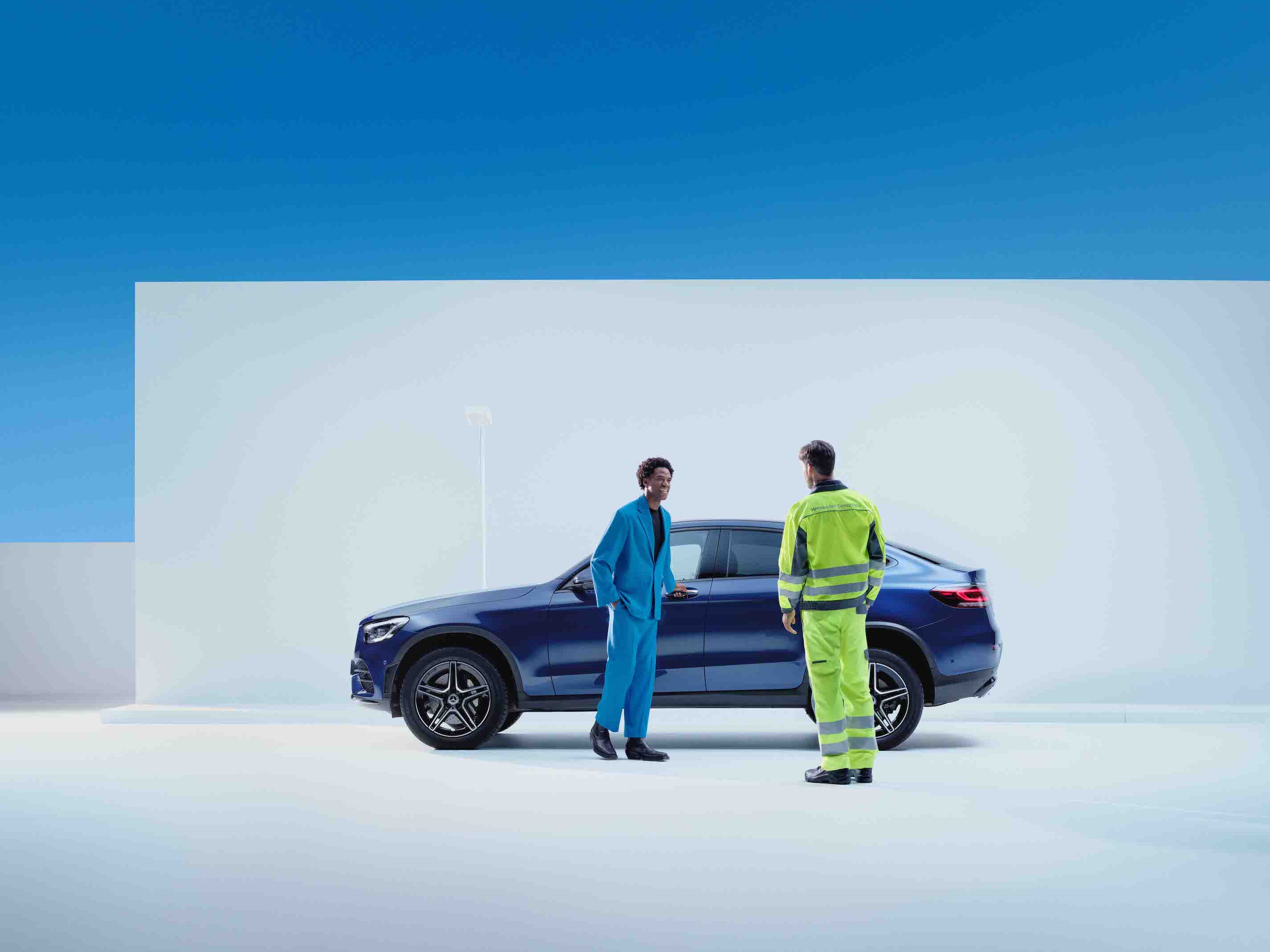 A man standing in front of a Mercedes-Benz with a service employee.