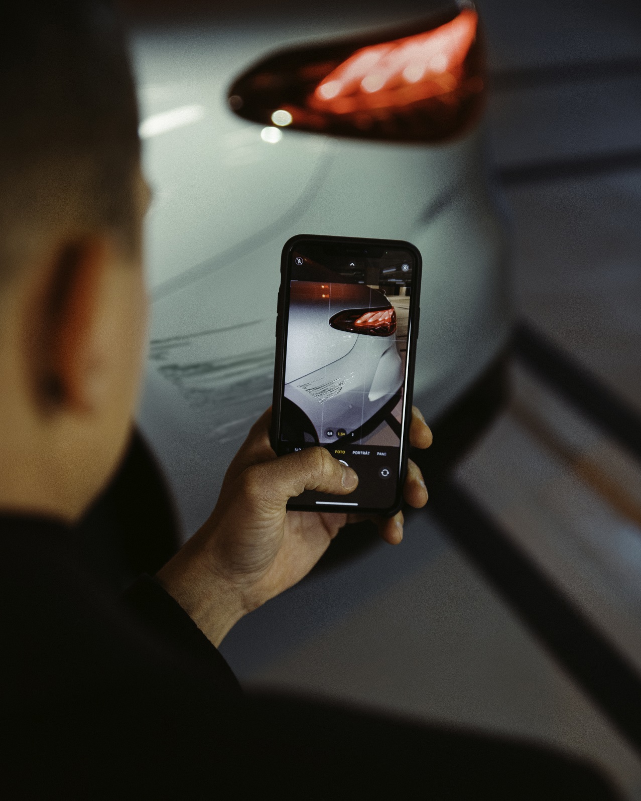 Damage Assistance | Breakdown Assistance Overview | Mercedes-Benz Using a smartphone, a man is photographing the damage to the rear wing of his Mercedes.