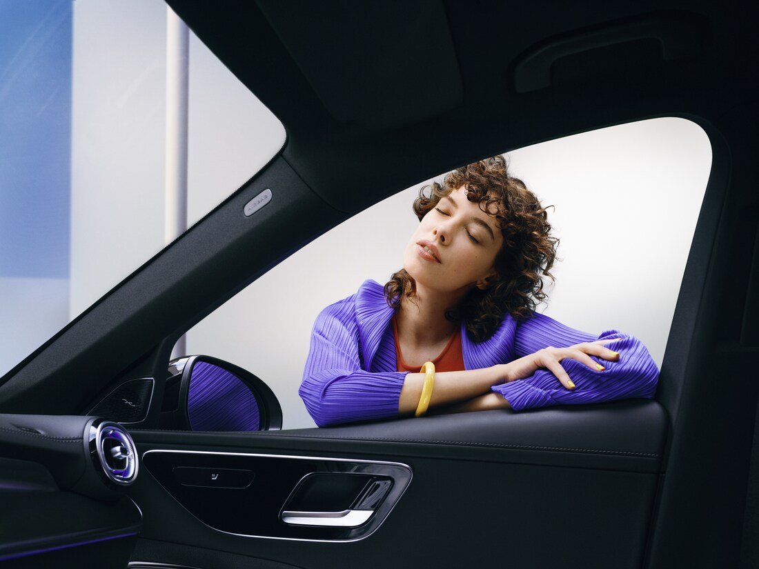 ผู้หญิงคนหนึ่งเพลิดเพลินกับรถยนต์ Mercedes-Benz ที่สะอาดของเธอ