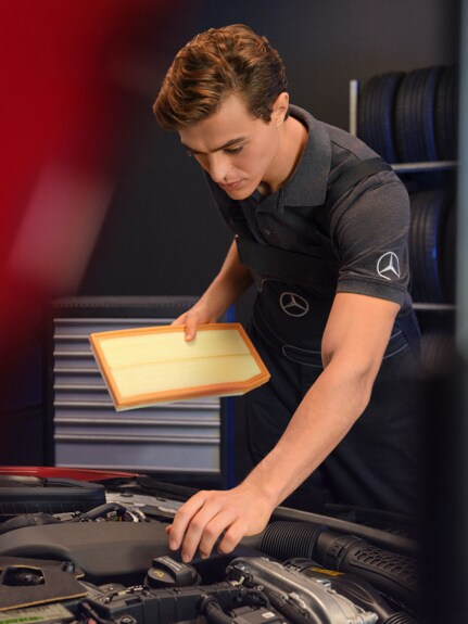 A Mercedes-Benz technician changes the air filter of a vehicle.