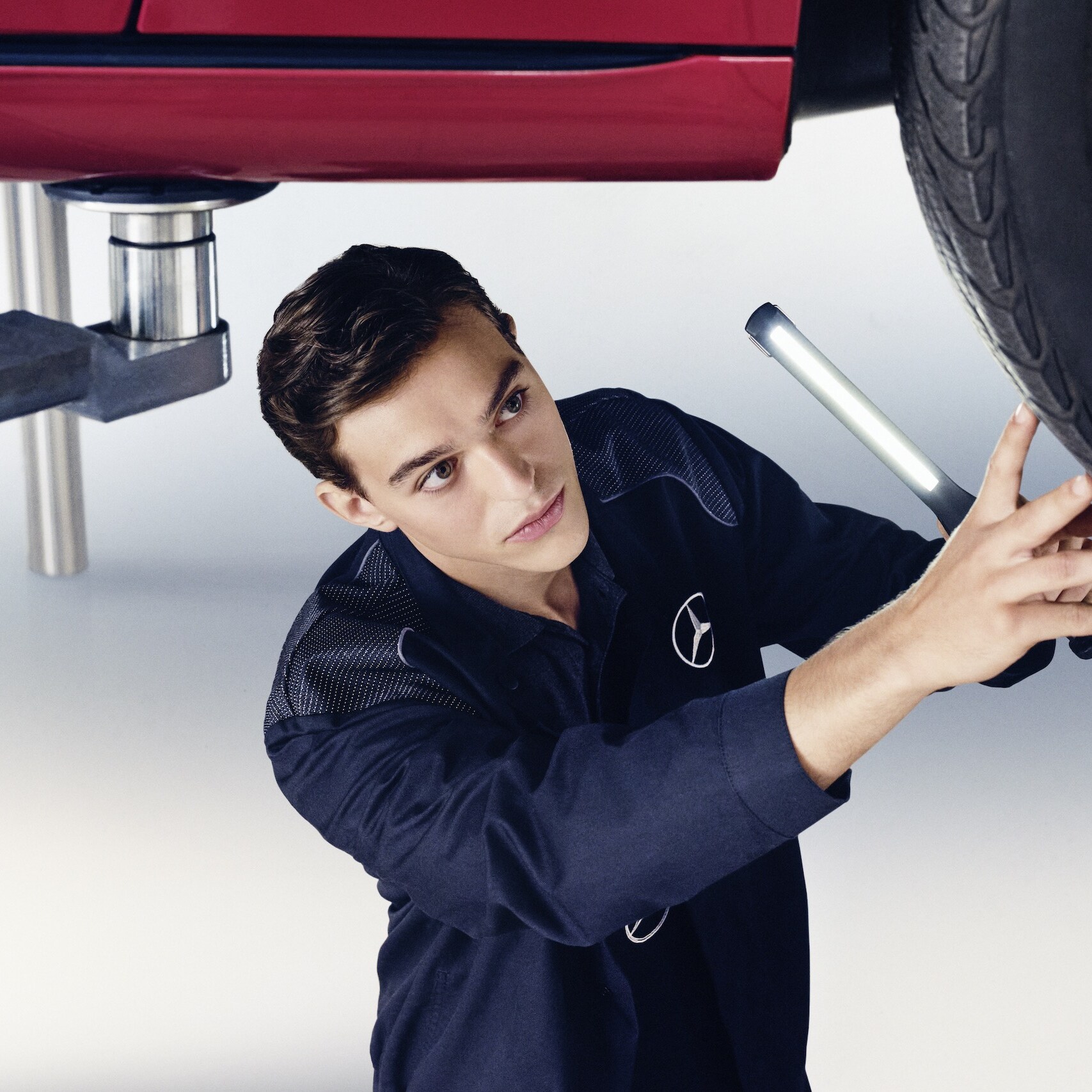 A Mercedes-Benz mechanic and a man stand in front of the open bonnet of a Mercedes-Benz.