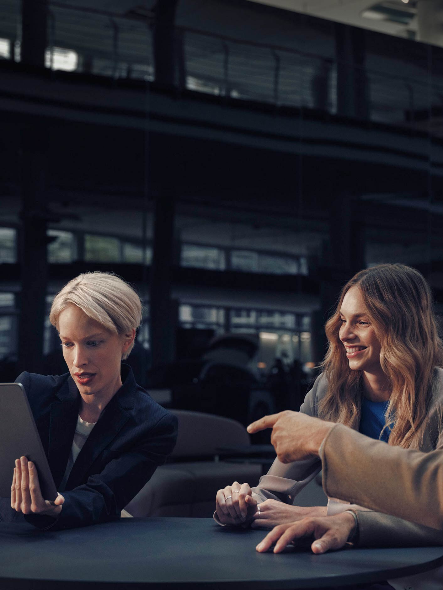A man and woman sitting at a table with a Mercedes-Benz dealer