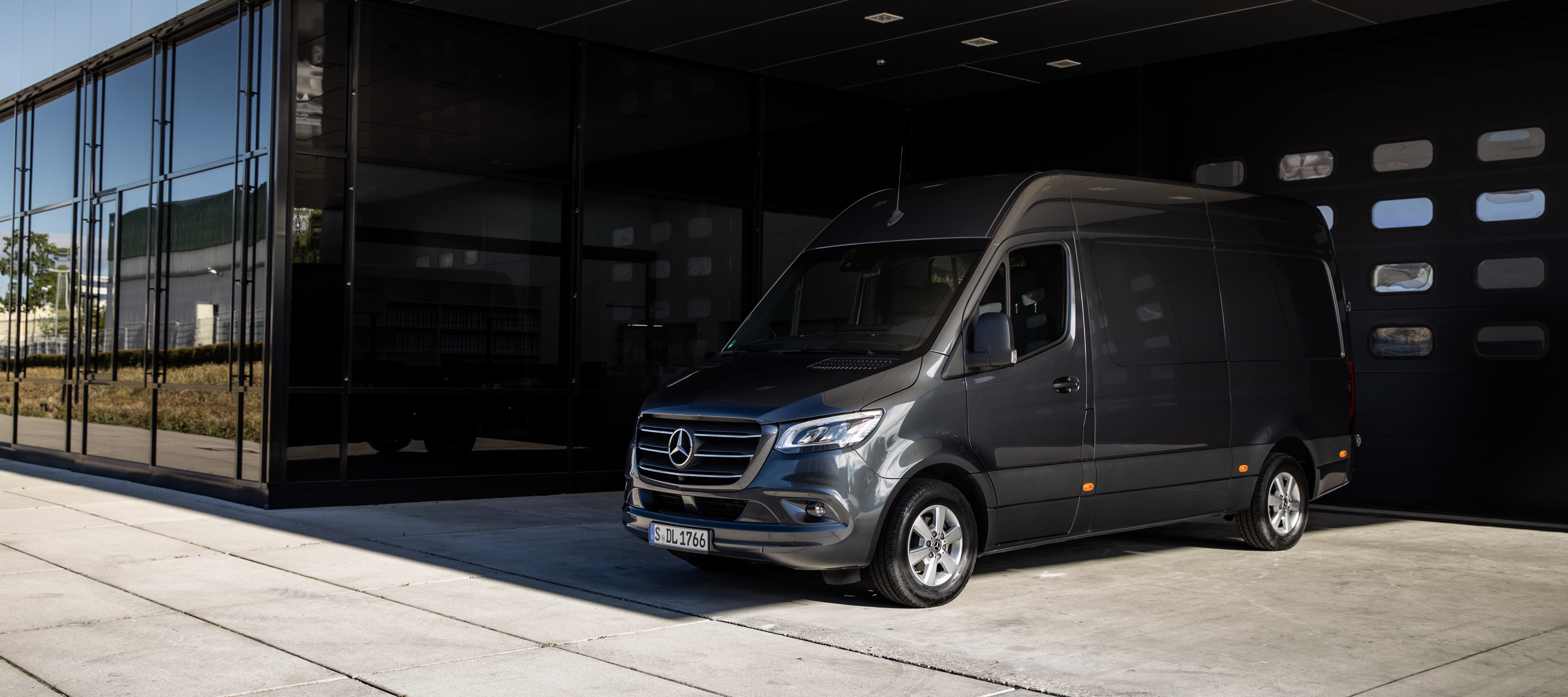 รถตู้บรรทุกแบบทึบ Sprinter | รถตู้ Mercedes-Benz รถตู้บรรทุกแบบทึบ Sprinter จาก Mercedes-Benz จอดอยู่ในลานที่ออกแบบมาอย่างทันสมัยหน้าประตูโรงรถ