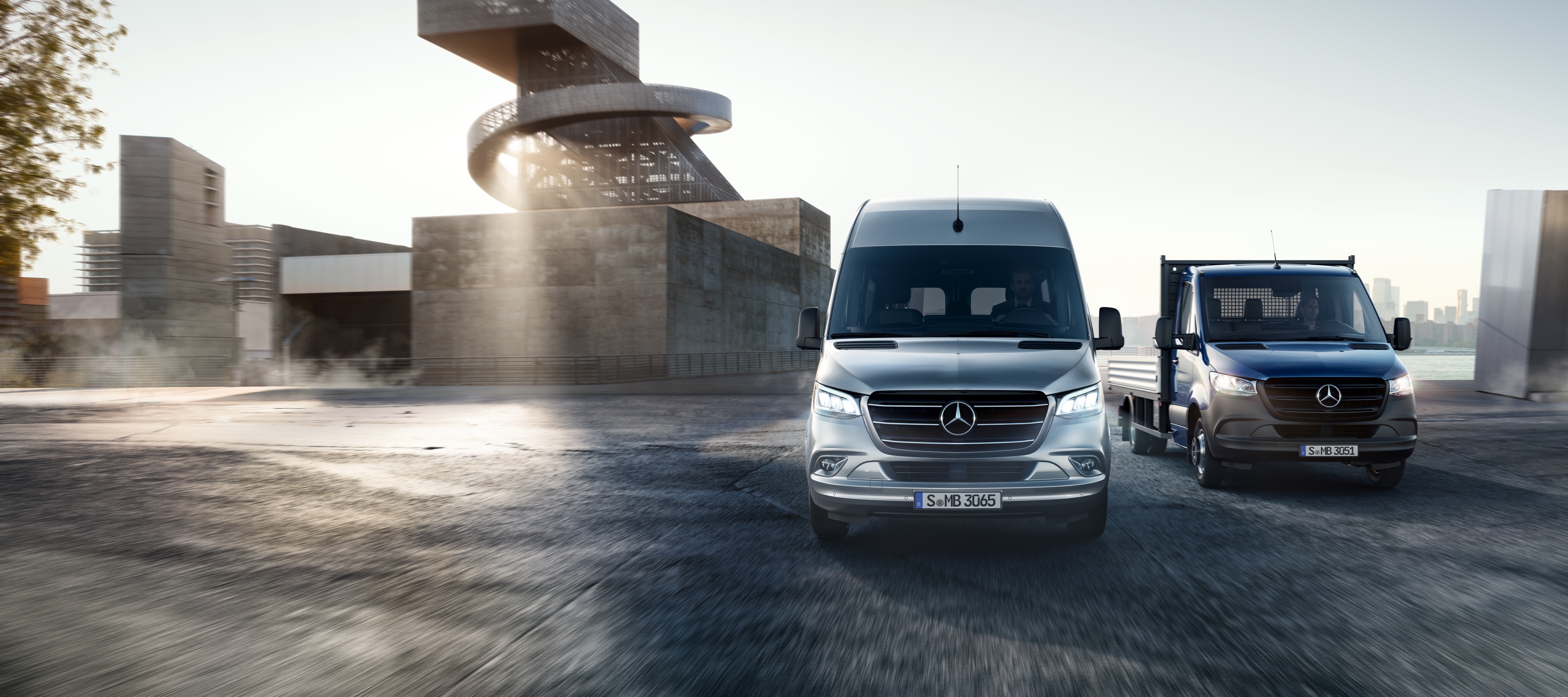 Sprinter | รถตู้ Mercedes-Benz Mercedes-Benz Sprinter ในรูปแบบกระบะบรรทุกและรถตู้บรรทุกแบบทึบ จอดข้างกันที่หน้ากลุ่มอาคารสมัยใหม่
