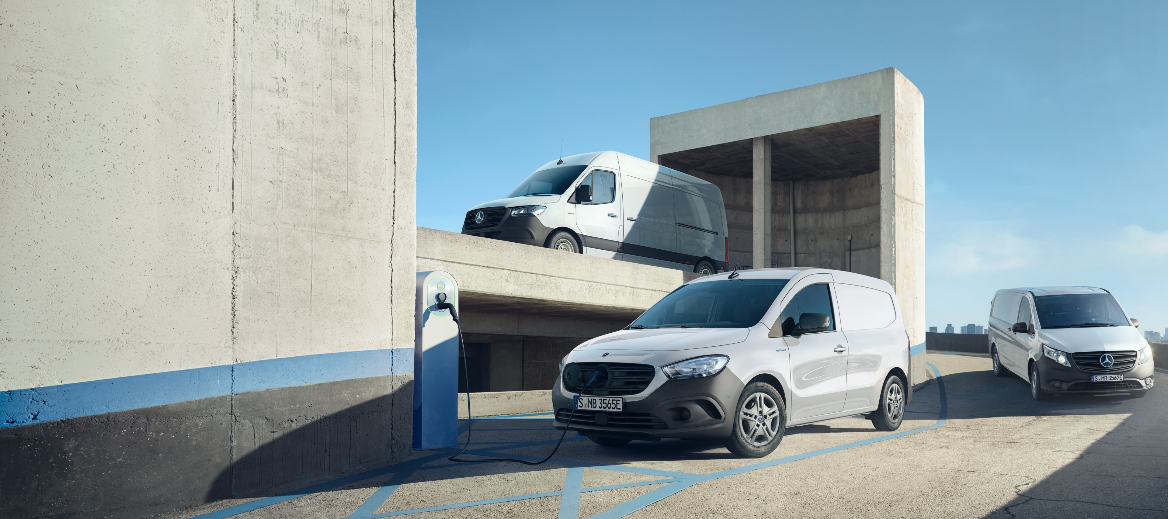 Electric Vans | Mercedes-Benz Vans The eSprinter, eVito and eCitan, electric vans from Mercedes-Benz, stand together in an urban environment.