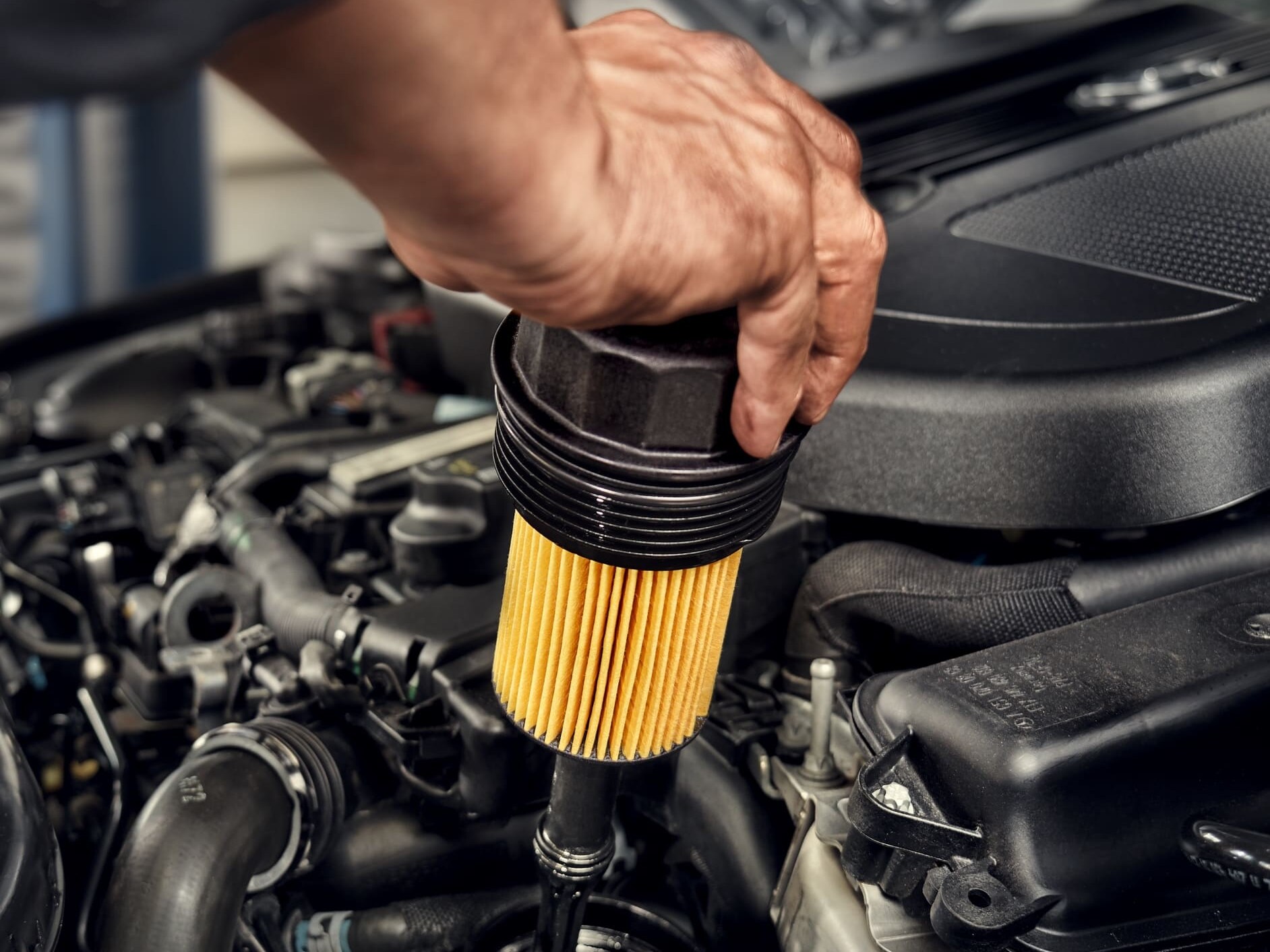 A Mercedes-Benz technician changes the oil filter in the vehicle.